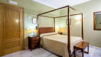 Una cama con dosel sobre un marco de madera, una mesita de noche y un armario de madera.