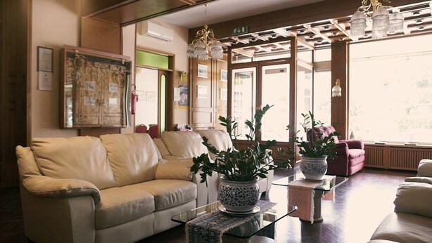 Una sala de estar con un sofá color beige, una mesa de centro de vidrio y dos plantas en macetas.