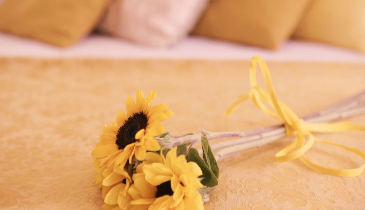 A bouquet of yellow flowers tied with a yellow ribbon on a textured surface.