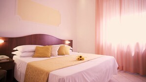 Una cama bien hecha con una colcha blanca y beige, dos almohadas y un adorno decorativo sobre la cama.