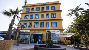 Ein Hotel mit gelbem Anstrich, zahlreichen Fenstern und einem Schild mit der Aufschrift "MIRAMARE HOTEL".