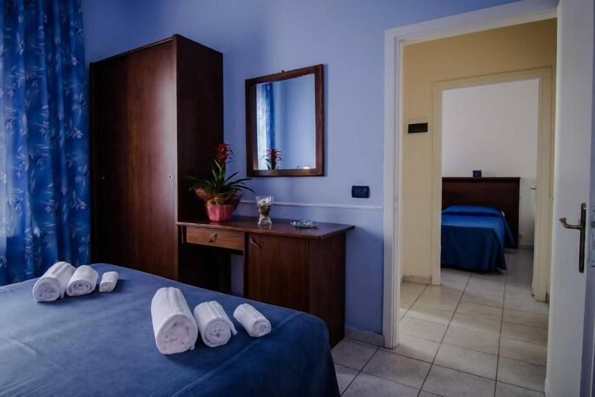 Una habitación de hotel con cama, escritorio, espejo y una planta en maceta.
