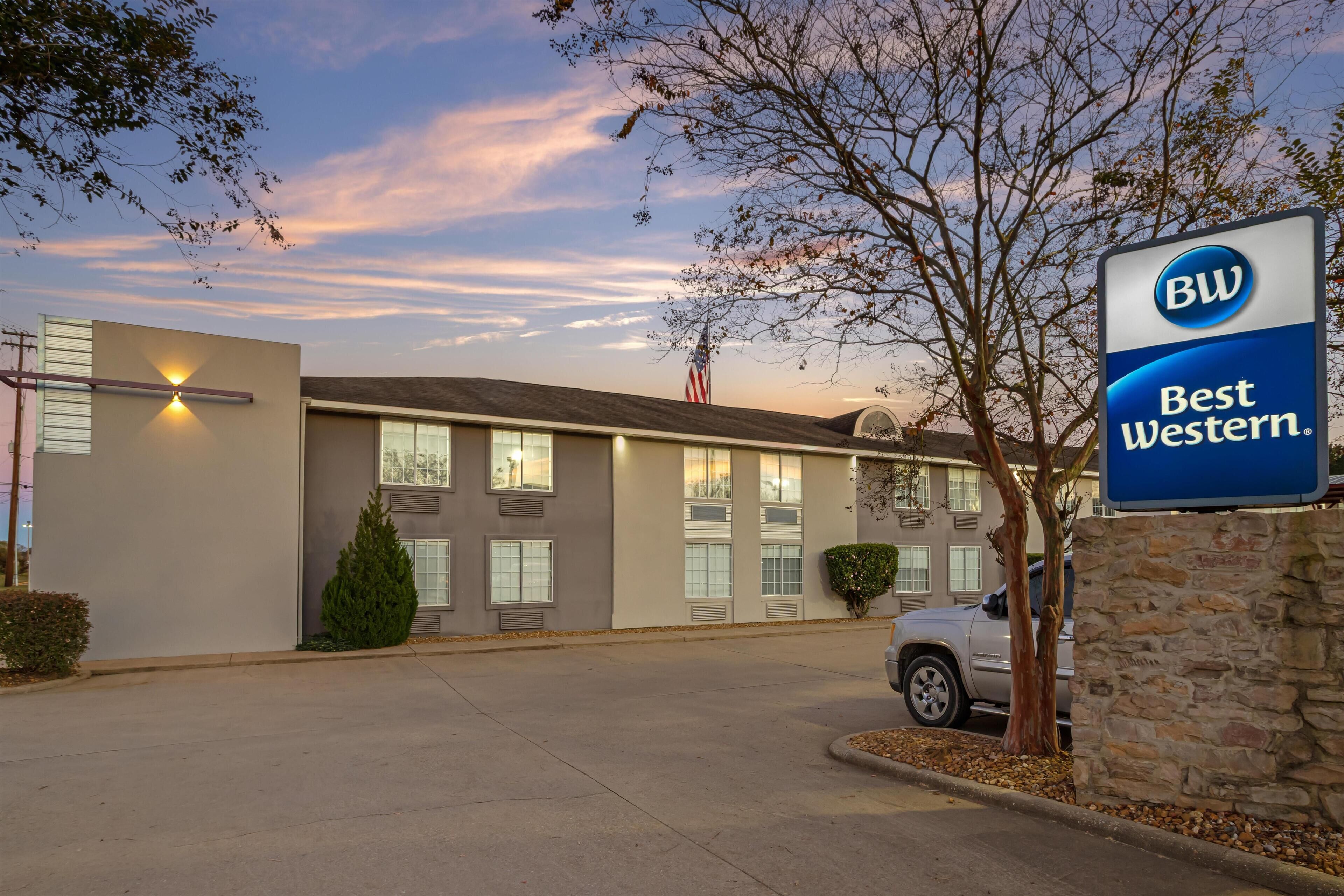 A Best Western hotel with a modern facade, a parking lot, and an American flag.