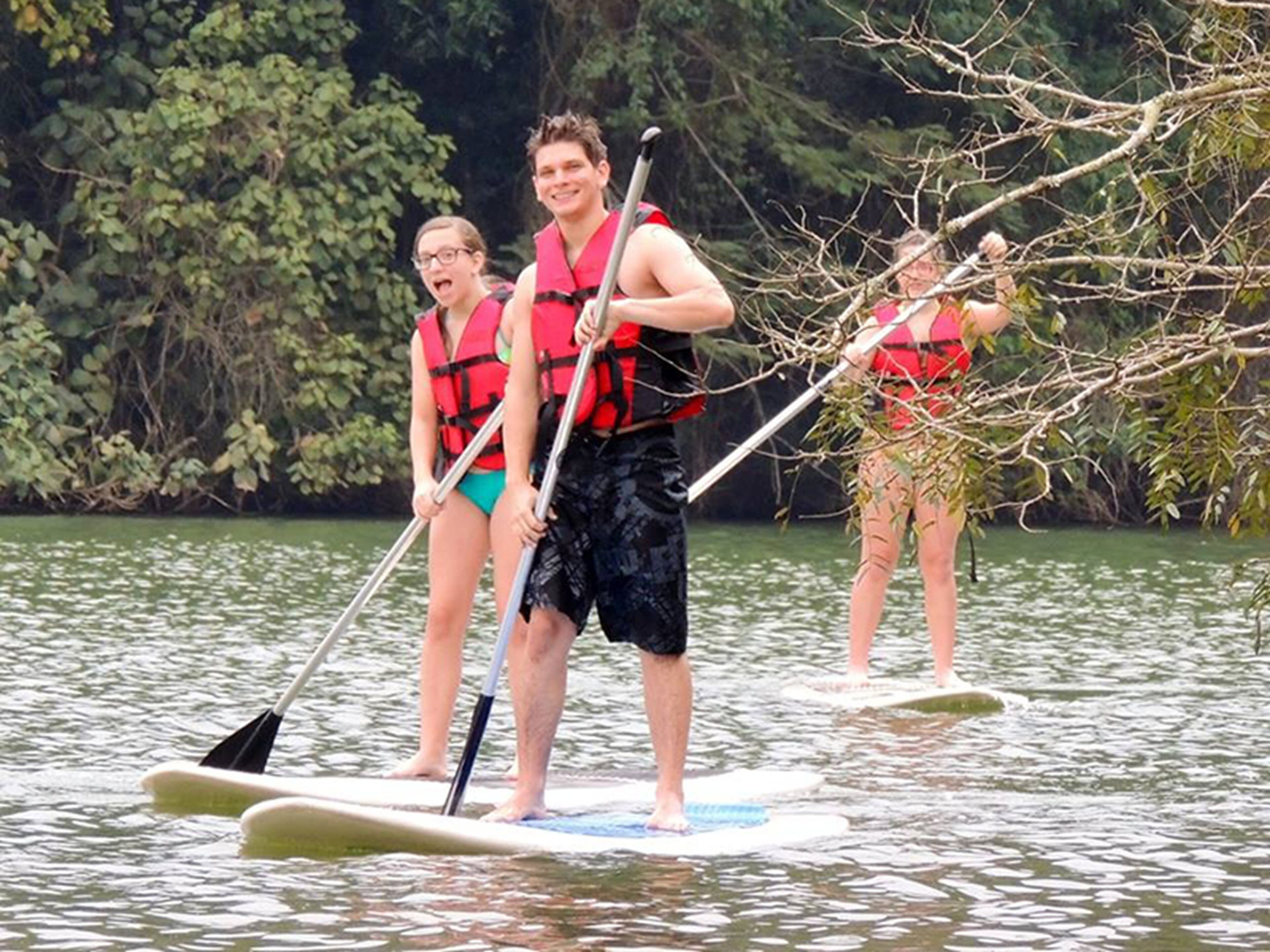 Three people on paddleboards in a calm body of water surrounded by greenery.