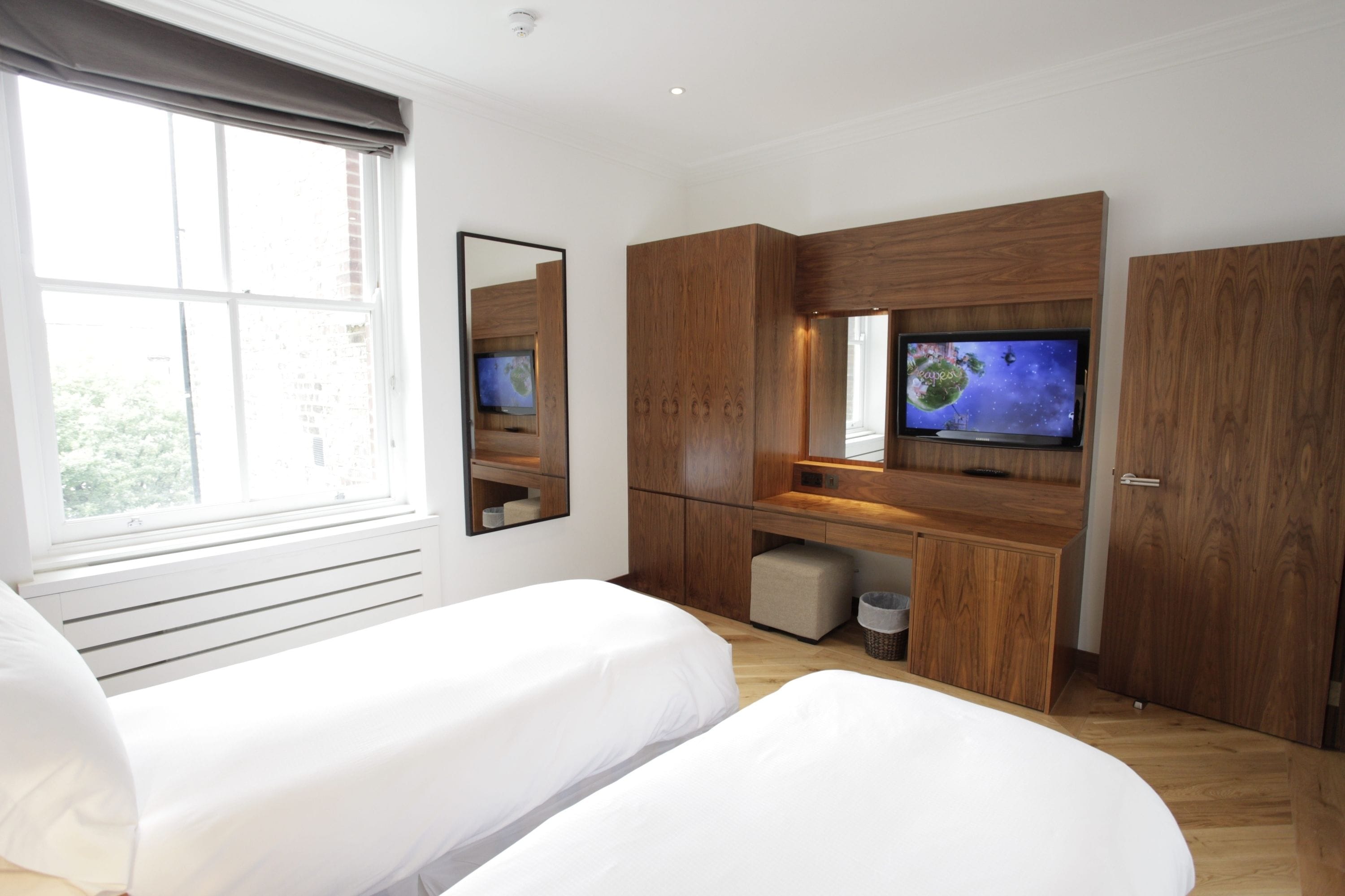 Un dormitorio moderno con dos camas, un televisor y muebles de madera.