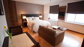 Een moderne hotelkamer met een groot bed, een bank, een eettafeltje en een aan de muur bevestigde televisie.