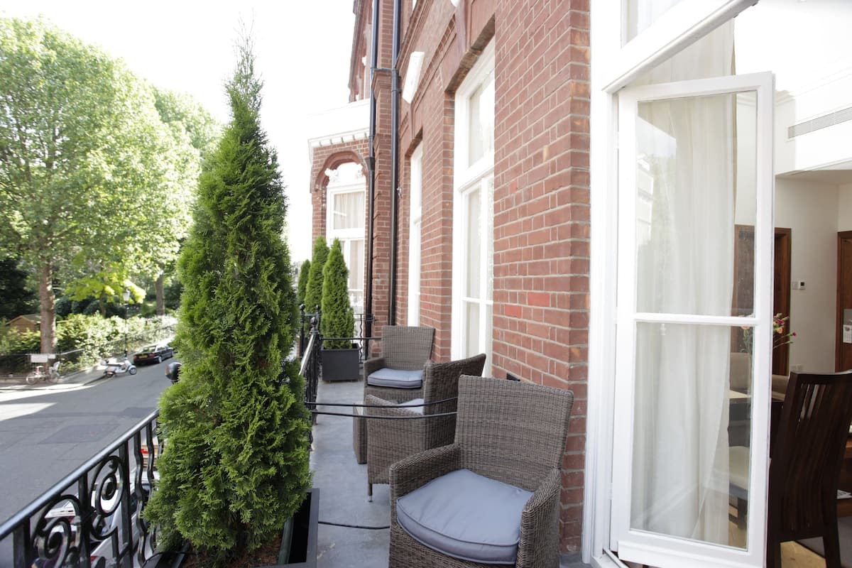 A balcony with wicker furniture and a tall conifer tree.