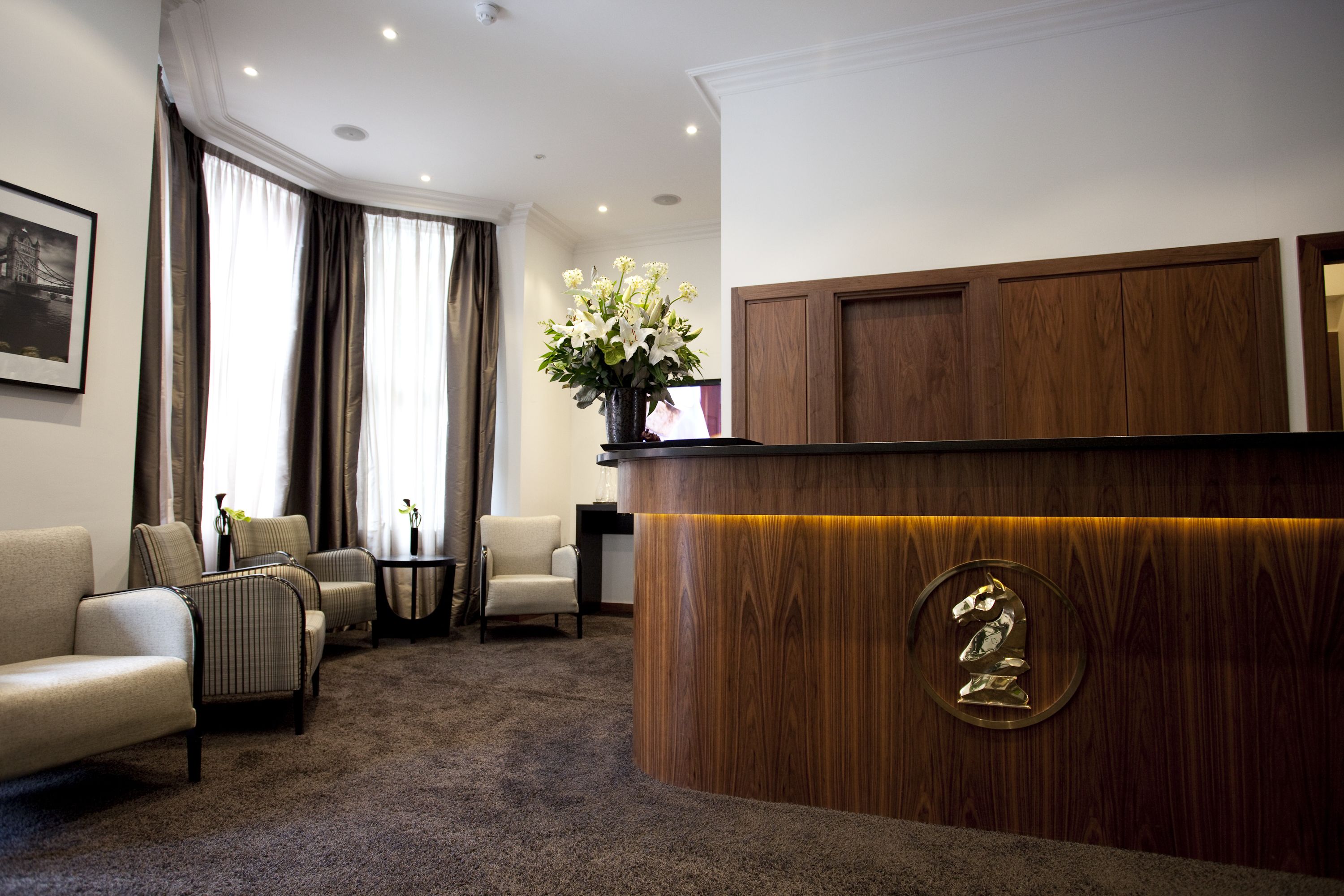 A reception area with a wooden reception desk, a potted plant, and a framed picture on the wall.