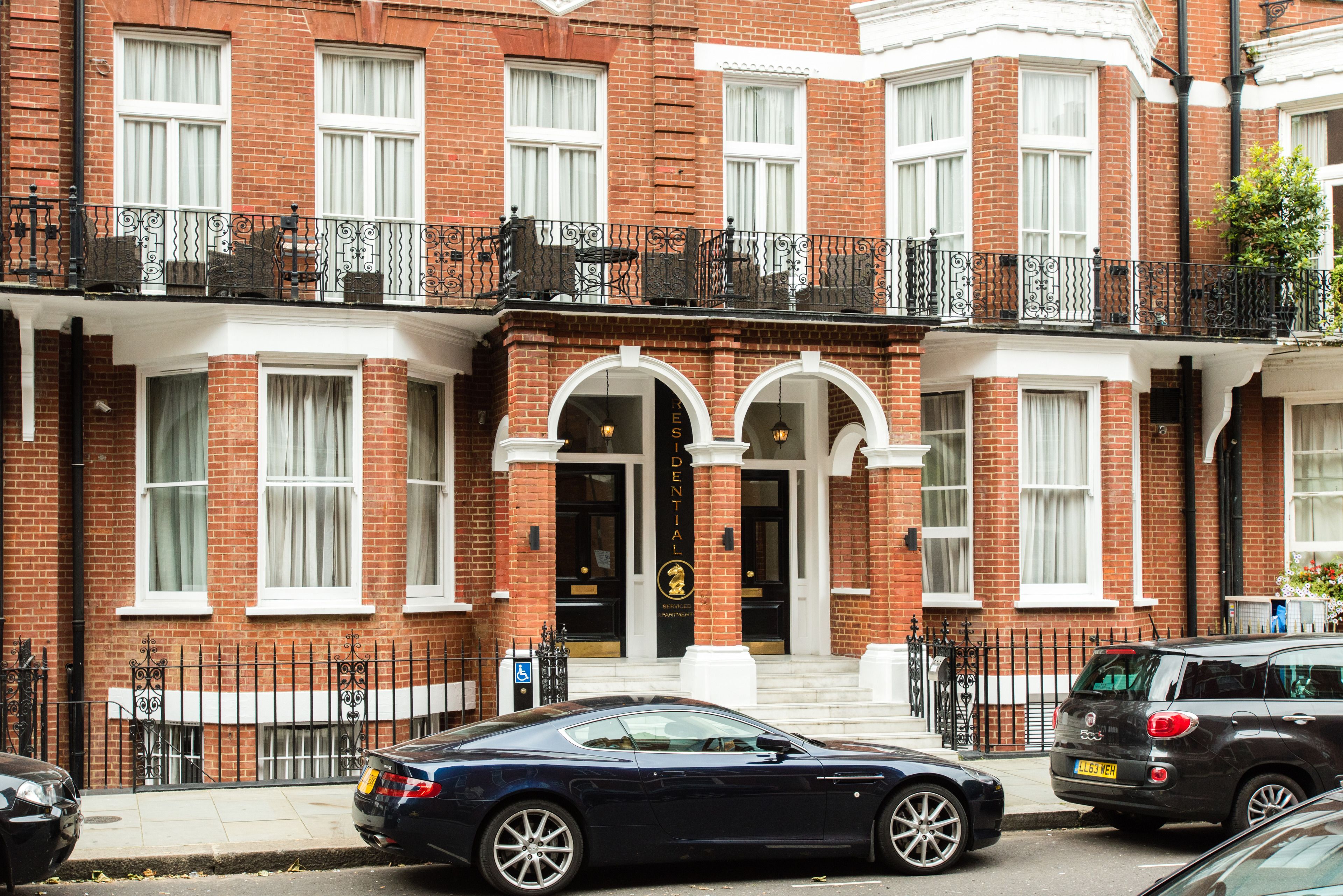 A red brick building with a black iron balcony, a black car parked in front, and a sign that reads "Dental".