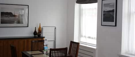 A dining area with a wooden table and chairs, a water bottle, and two framed pictures on the wall.