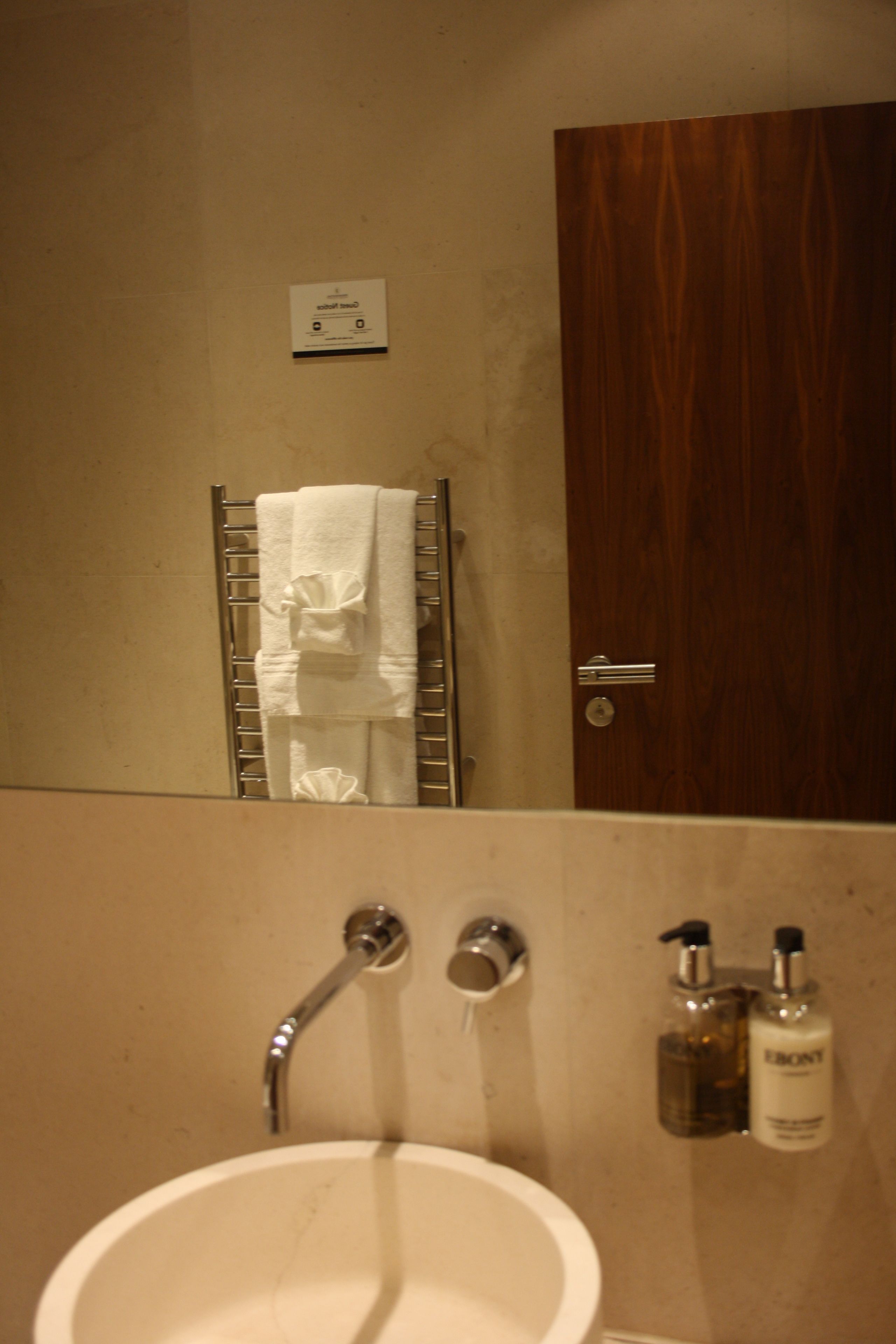 A bathroom with a sink, towel rack, and two bottles of toiletries.