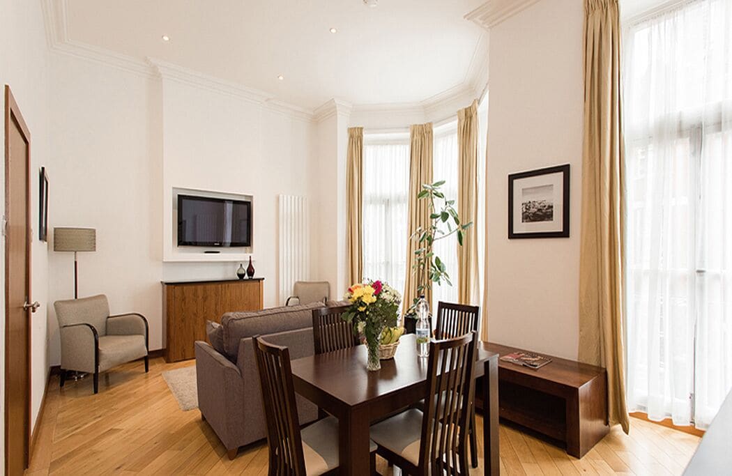 Ein modernes Wohnzimmer mit einem Holzesstisch, Sofas und einem flachbildfernseher an der Wand.