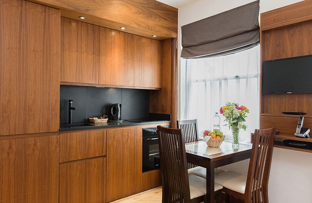 Eine moderne Küche mit Holzschränken, einer schwarzen Arbeitsplatte und einem Essbereich mit Tisch und Stühlen.