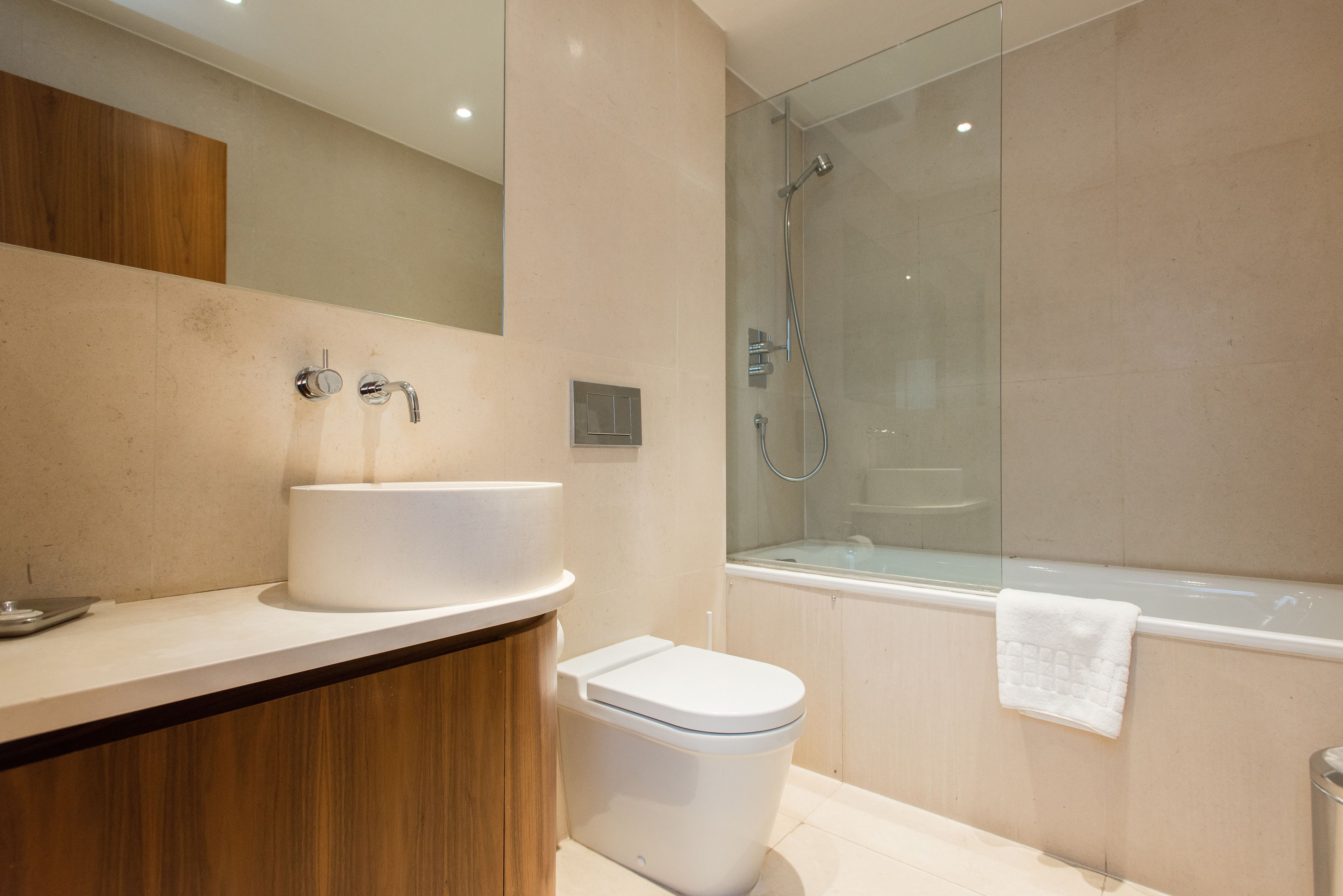 Un baño moderno con lavamanos, inodoro y zona de ducha con mampara de vidrio.