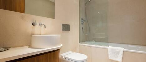 Un baño moderno con lavamanos, inodoro y zona de ducha con mampara de vidrio.