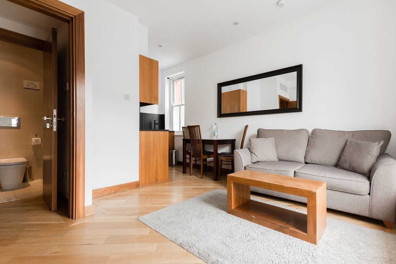 Un salon moderne comprenant un canapé, une table basse en bois et un coin repas avec des chaises et une table.