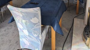 Una stanza con una parete grigia, un divano nero, un divano blu e un tavolo con un telecomando.