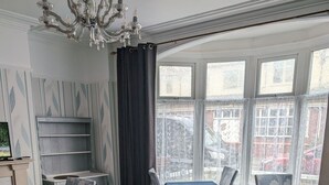 Zona pranzo con tavoli e sedie, ampie finestre e un lampadario.