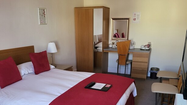 Camera d'albergo con un letto grande, una scrivania, una sedia e un tavolino.