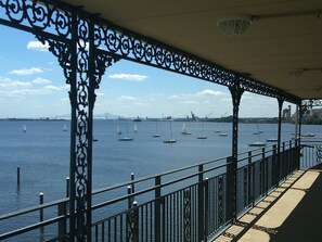 A covered waterfront promenade with ornate metal railings and a view of sailboats on the water. - Waterfront Inn PHL Airport (Essington)