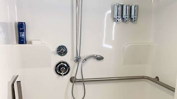 A modern bathroom with a bathtub, a handheld showerhead, and a grab bar.