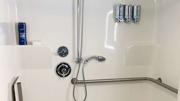 Un baño moderno con bañera, ducha de mano y barra de apoyo.
