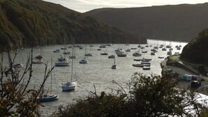Um porto com vários barcos atracados na costa, rodeado por colinas.