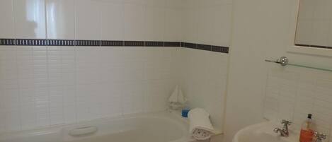 A bathroom with a bathtub, a sink, and a mirror.