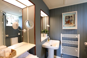 A bathroom with a white sink, mirror, and towel rack. There is a potted plant on the counter and a framed picture on the wall. - Sheridan Guest House (Edinburgh)