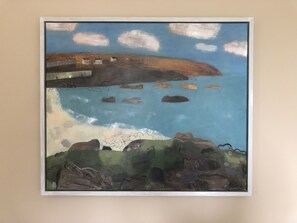 A framed painting of a coastal landscape with houses, a bridge, and rocky outcrops. - Sheridan Guest House (Edinburgh)
