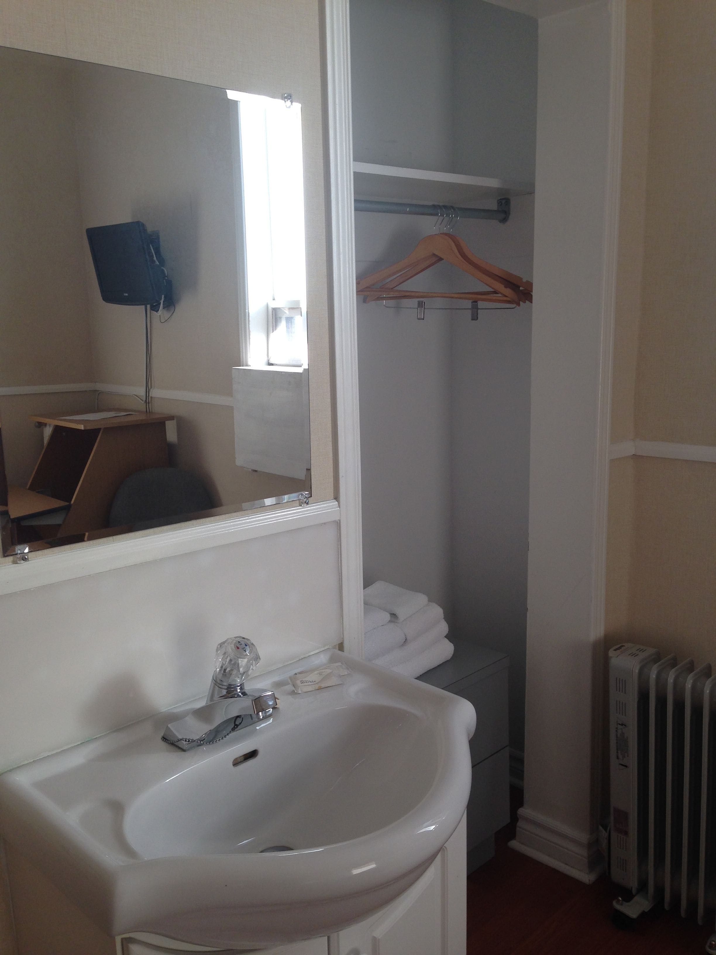 A bathroom with a sink, mirror, and towel rack.