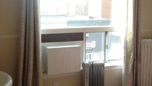 Una habitación con ventana, radiador y televisor montado en la pared.