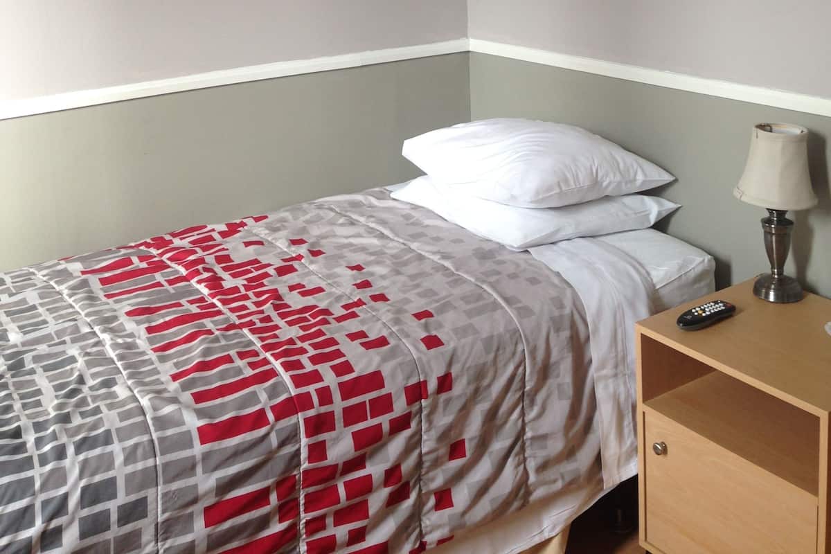 A bedroom with a bed, a nightstand, a lamp, and a painting on the wall.
