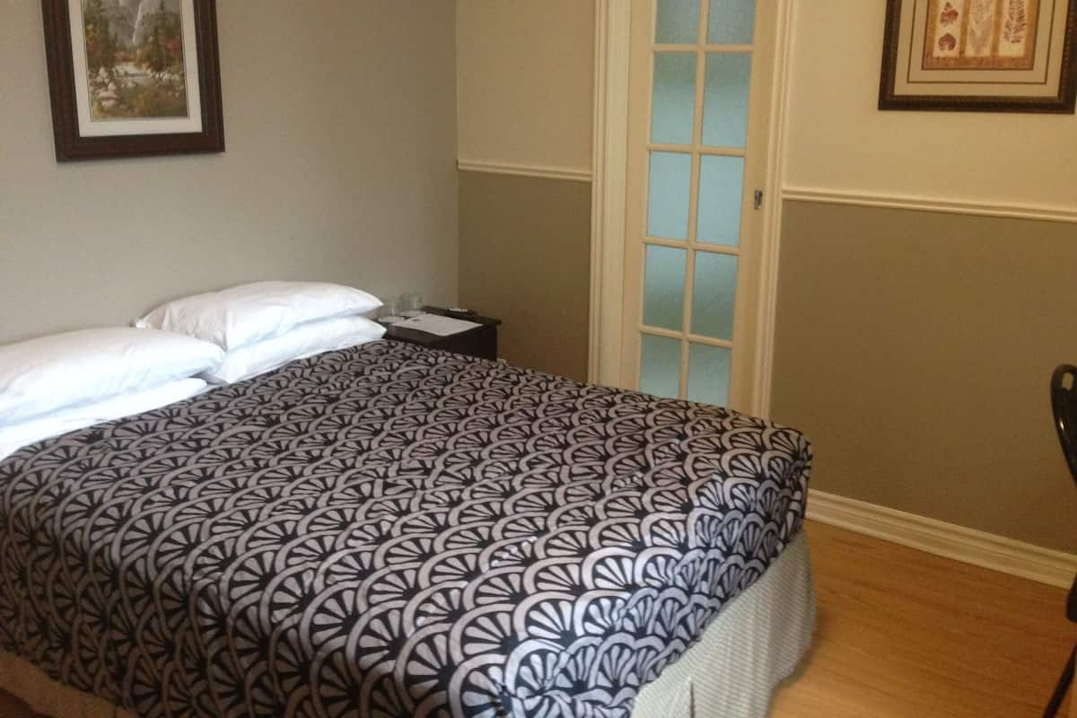 A bedroom with a bed, a nightstand, a door, and a framed picture on the wall.