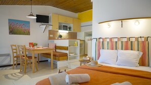 A hotel room with a bed, a desk, a chair, a television, and a microwave.