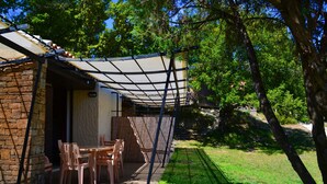 A stone building with a covered patio area, outdoor seating, and a view of a lush green landscape.