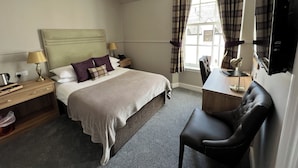 A hotel room with a bed, bedside tables, a desk with a chair, a flat-screen TV, and a window with curtains. - Cove Bay Hotel (Aberdeen)