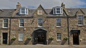 A stone building with a main entrance, a corner window, and a sign that reads "Care Bay Hotel". - Cove Bay Hotel (Aberdeen)