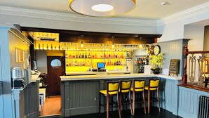 A bar area with a counter, bar stools, and a variety of bottles and glasses. - Cove Bay Hotel (Aberdeen)