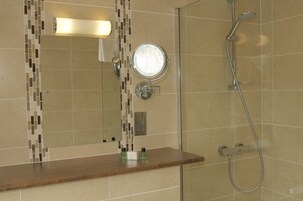 A bathroom with a mirror, a shower, and a vanity with toiletries.