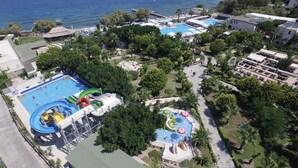 Vista aérea de un complejo turístico con múltiples piscinas, toboganes acuáticos y abundante vegetación.