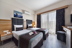 Una habitación de hotel con dos camas, un escritorio, una silla, un televisor y un cuadro en la pared.