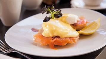 A plate with smoked salmon, hollandaise sauce, and a lemon slice.