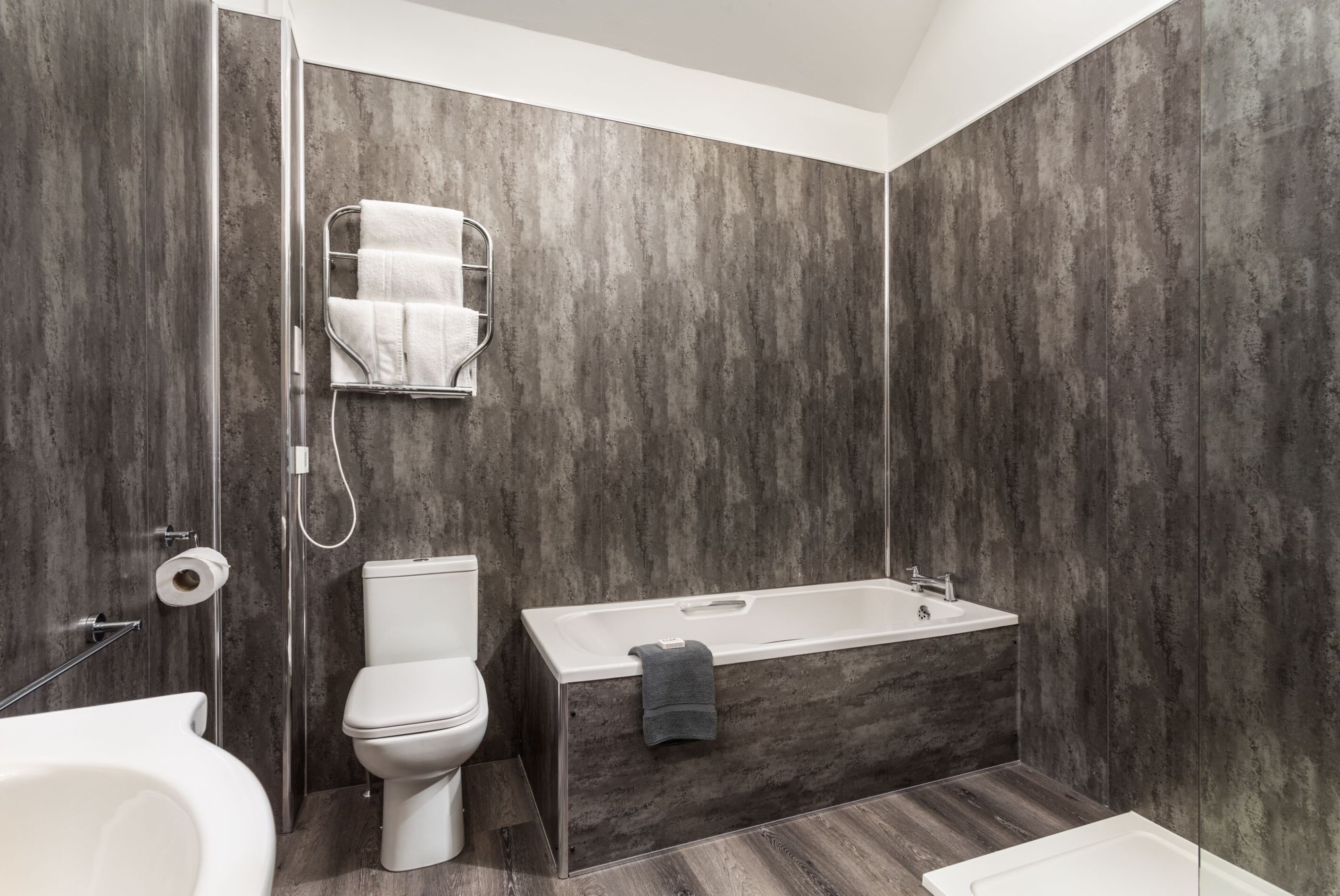 Et moderne badeværelse med toilet, badekar og bruseniche.