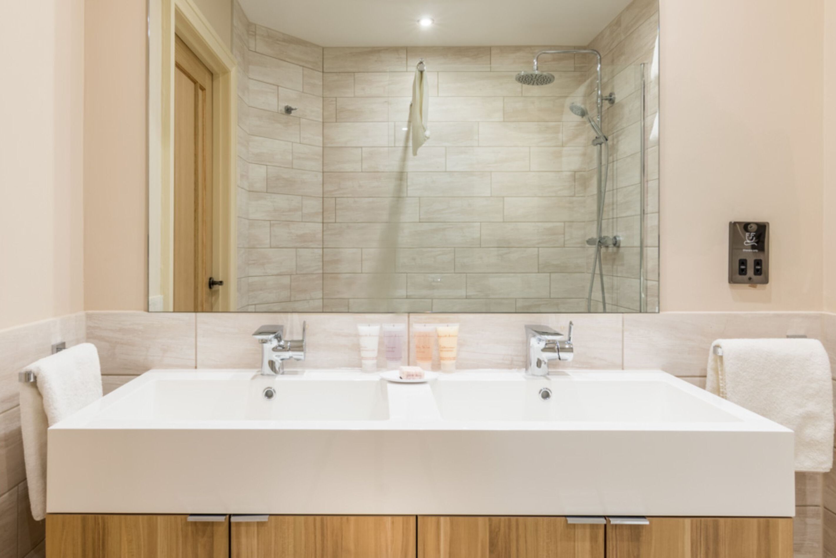 A modern bathroom with a large rectangular sink, a glass shower enclosure, and a wooden vanity.