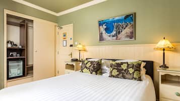 A hotel room with a bed, a nightstand with lamps, a wardrobe, and a painting on the wall.