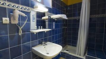 Un baño con lavamanos blanco, ducha con cortina y un perchero para toallas.