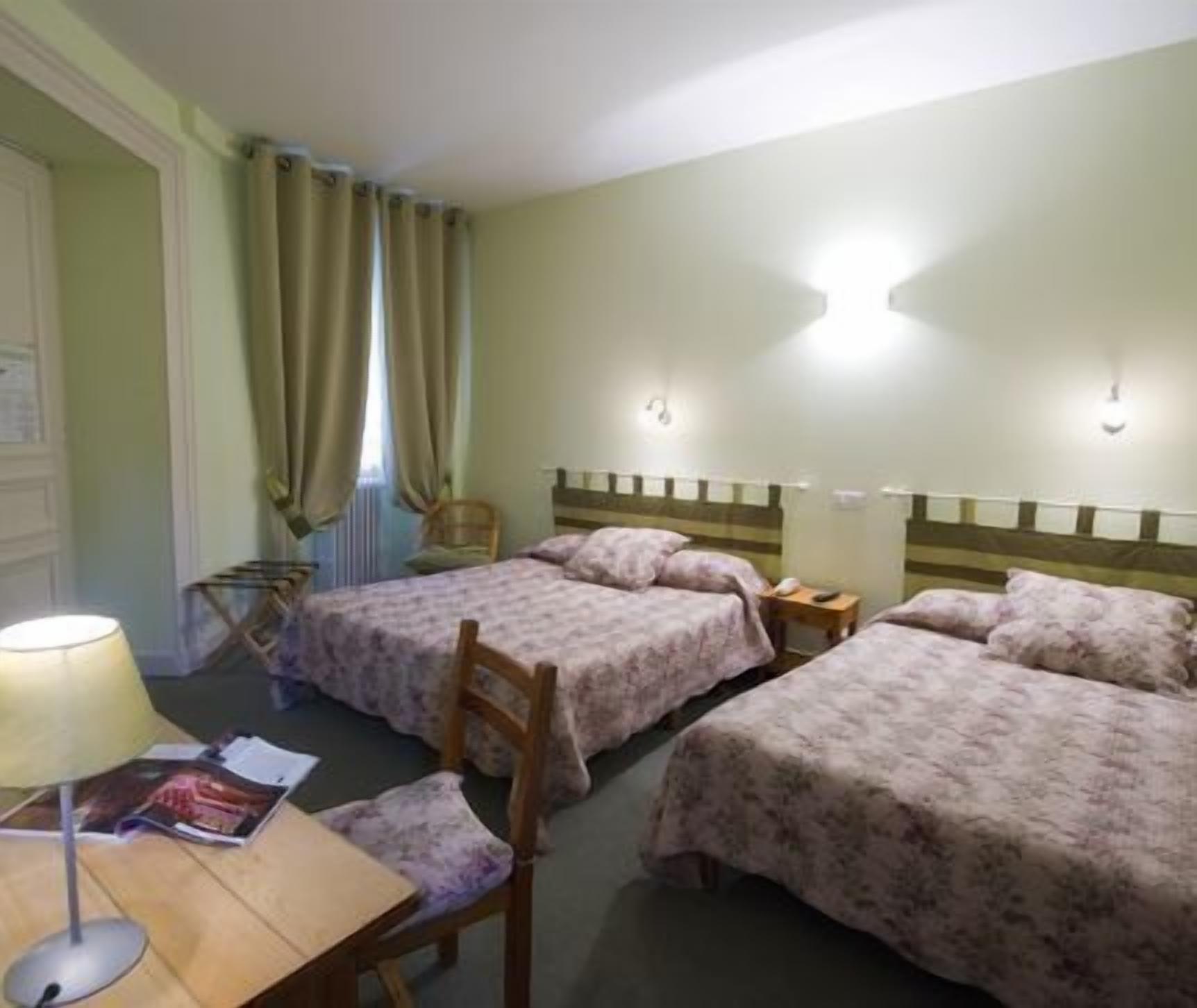 Een hotelkamer met twee bedden, een stoel, een tafel en een lamp.