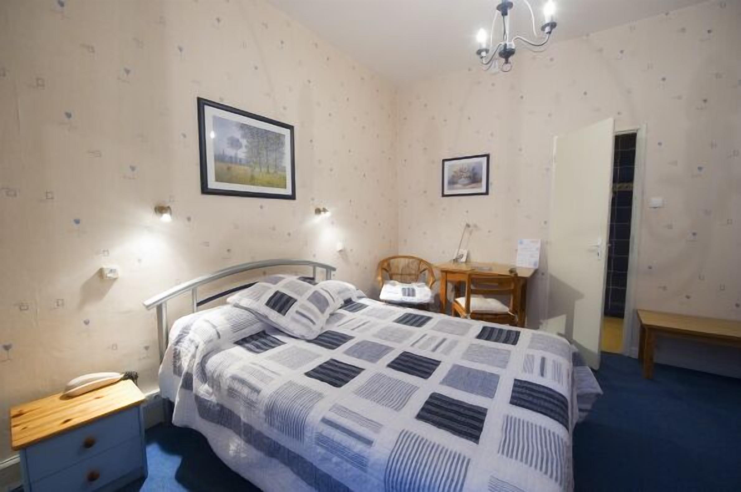A bedroom with a bed, bedside table, lamp, and a framed picture on the wall.