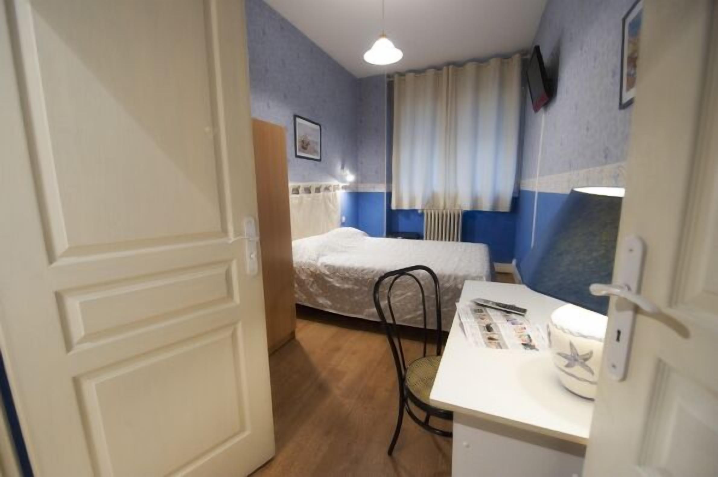 Una habitación pequeña y funcional con cama, escritorio y silla.